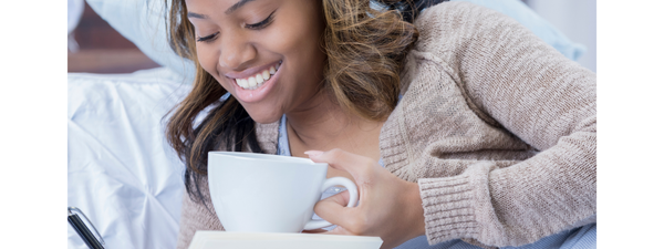 A Black woman drinking tea and writing