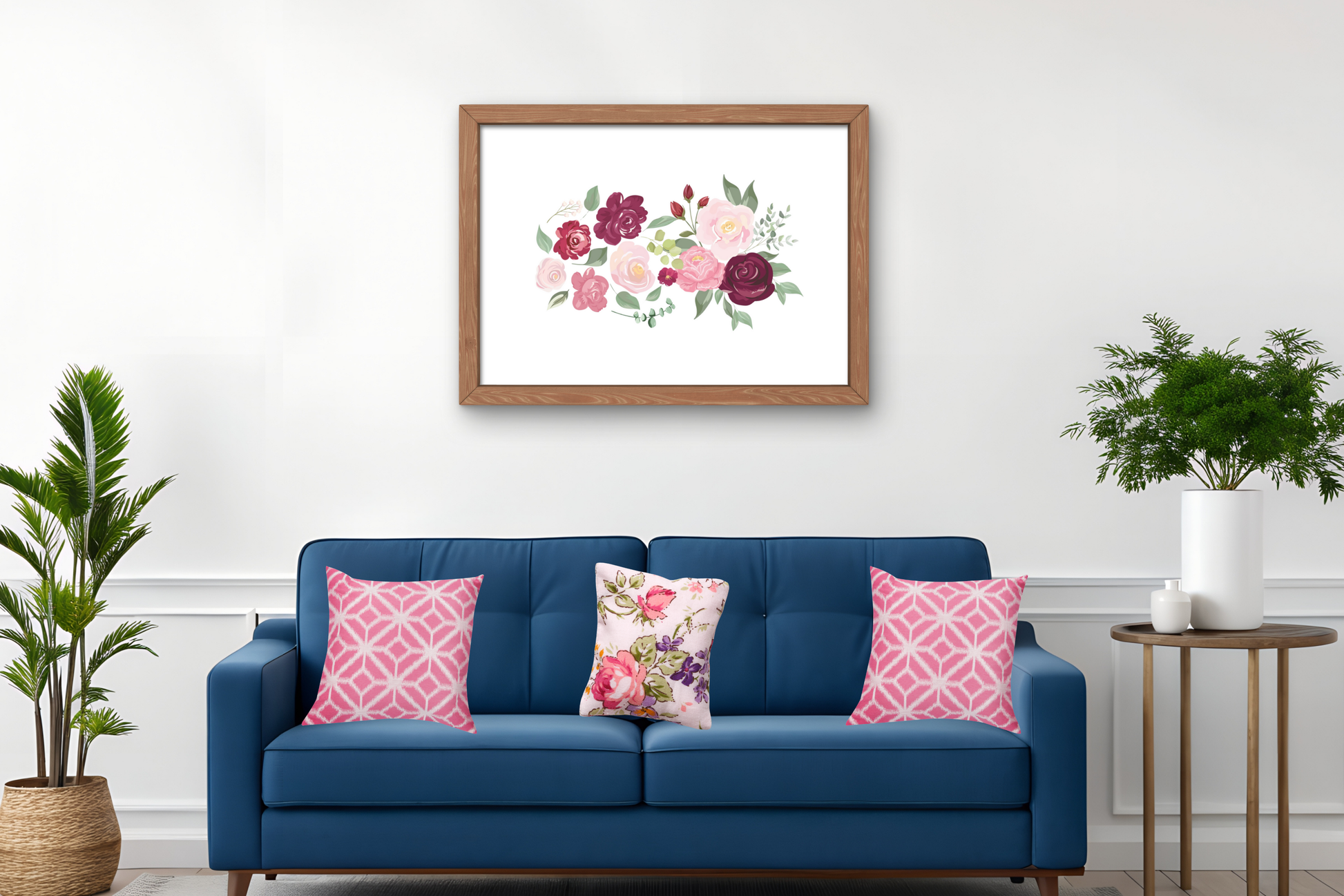 The feminine floral wall art print featuring soft blush and berry roses with elegant green foliage, framed in white or gold and styled above a neutral sofa to create a calm, luxurious atmosphere.