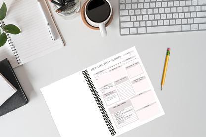 First page of the Soft Life daily planner journal open on a feminine office table with a cup of coffee, laptop and pencil.